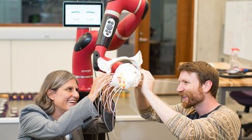 faculty members adjusting a robot with whiskers