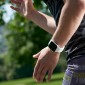 A man or woman runs on a sunny day with their Apple Watch on their wrist.