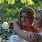 Two women in white dresses embrace on their wedding day