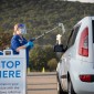 A woman hands a COVID-19 testing kit to a vehicle at a testing center at the Walmart Supercenter in Elizabethville, PA. 