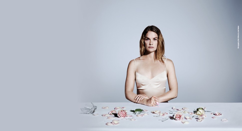 The production banner shows a woman sitting at a table that has flowers on it.