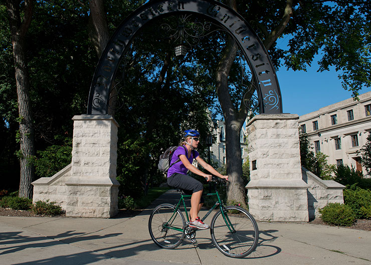 A cyclist rides a bike at Weber Arch on Northwestern's campus. 