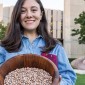 Odette Zero holding a bowl of beans in front of University Library.