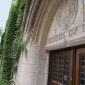 A doorway at the Northwestern University Pritzker School of Law with the school's classic insignia above a wooden double door and beneath a curved archway