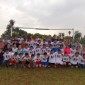 A group photo shows many young people, both boys and girls, wearing matching T-shirts and posing in front of a soccer goal.