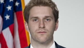 Male political candidate with flag behind him
