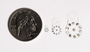 Three variations of the sticker, shown next to a quarter for scale