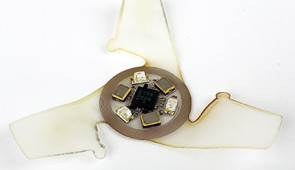 Top of microflier with coil antenna and sensors to detect ultraviolet rays.