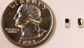 Two pacemakers next to a quarter for scale.