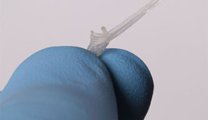 Fingers hold the soft, flexible device's cuff, which softly wraps around the nerve without needing sutures.