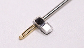 Pacemaker next to the eye of a sewing needle for scale.