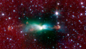 A young protostar in L483 and its signature outflow peeks out through a shroud of dust in this infrared image from NASA's Spitzer Space Telescope. Stars are known to form from collapsing clumps of gas and dust, or envelopes, seen here around a forming star system as a dark blob, or shadow, against a dusty background. The greenish color shows jets coming away from the young star within. The envelope is roughly 100 times the size of our solar system. Astronomers believe that the irregular shape of the envelope might have triggered the formation of twin, or binary stars in this system.