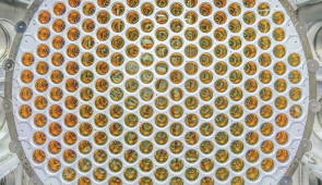 Large detector component filled with dozens of gold-colored photosensors, with cables and additional scientific equipment visible in the background