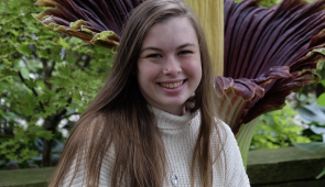 Olivia Murrell sits in front of a corpse flower.