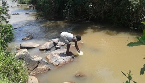 Woman collecting water from a river. Credit: Patrick Mbullo