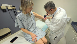 Dr. Pedram Gerami examines the skin of patient and melanoma survivor Heidi Tarr