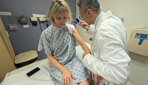 Dr. Pedram Gerami examines the skin of patient and melanoma survivor Heidi Tarr