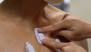 A health care worker sticks wearable devices onto an adult patient's chest. Credit: Northwestern Medicine