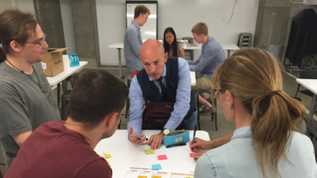 Marc McLaughlin, partner at Business Models, Inc., gives feedback to students Sofya Akhmametyeva (right), Austin Speelman (middle) and Nathan Corwin, who run the startup AIR, during summer Wildfire 2016 at The Garage