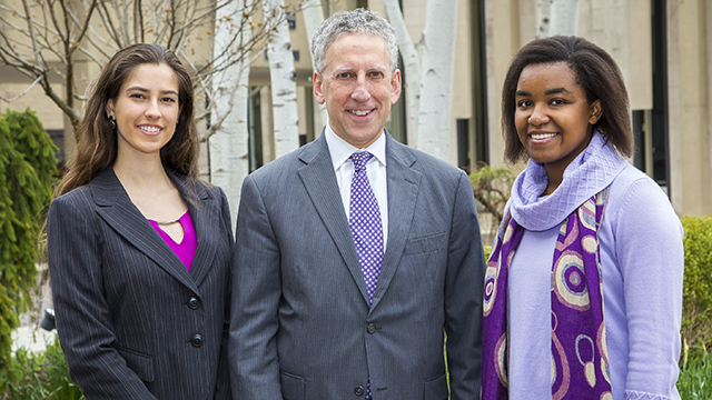 Two young women and a man pose for a picture.