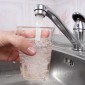 A hand holds a glass under a water faucet