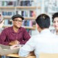 A group of people sit at a table in a library