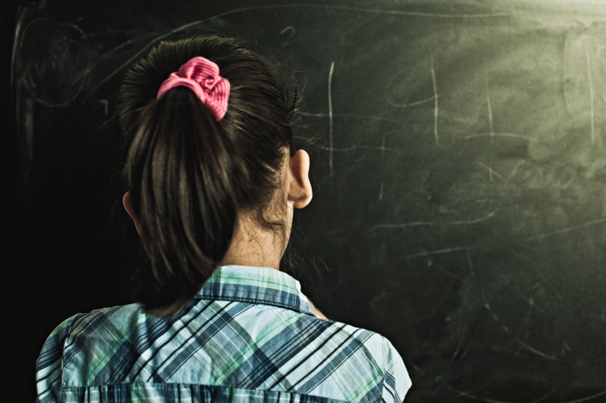 A girl stands at a chalkboard