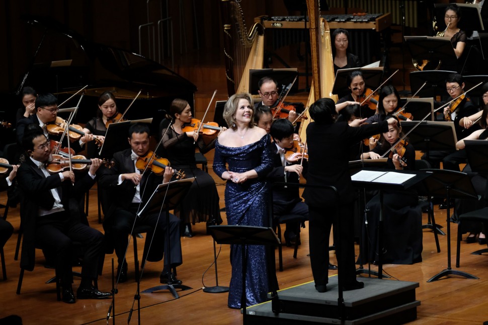 Renée Fleming stands on a stage among orchestra members