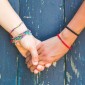 Two arms wearing bracelets holding hands