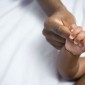 An adult holds a baby's hand