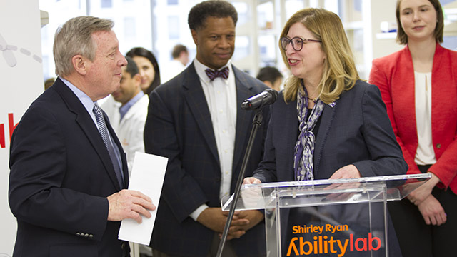 Durbin (left), Dr. Robert Winn, director of the University of Illinois Cancer Center, and Woodruff (at the podium).