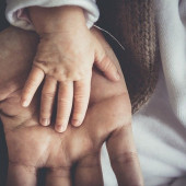 A dad holds a baby's hand