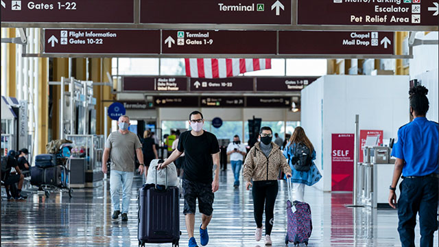 Masked travelers walking through an airport