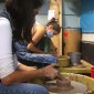 Two students molding clay on a pottery wheel