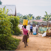A young woman carrying water containers to a village