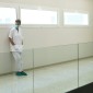 A healthcare worker leans against a wall in an empty corridor