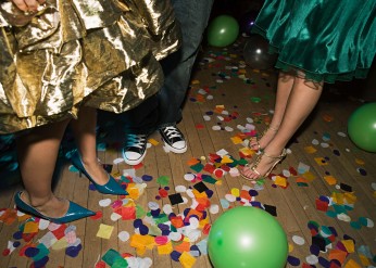 Three people dance on a confetti-strewn floor