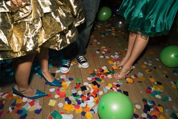 Three people dance on a confetti-strewn floor