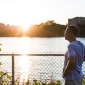 A man looks out onto a river during sunset