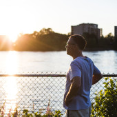 A man looks out onto a river during sunset