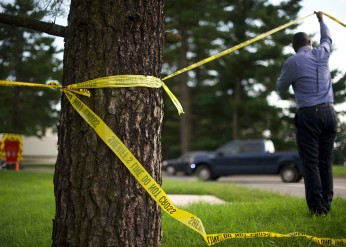 Crime scene tape tied around a tree flutters in the wind