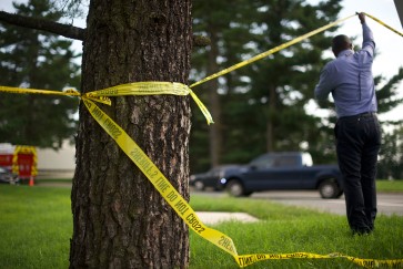 Crime scene tape tied around a tree flutters in the wind