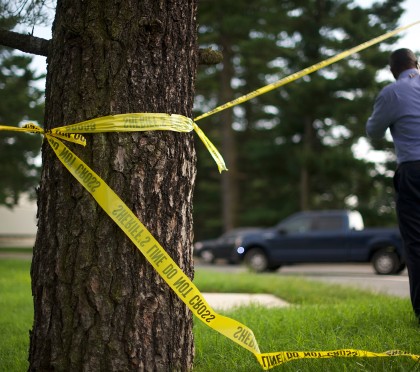 Crime scene tape tied around a tree flutters in the wind