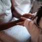 A doctor holds a Black patient's hands 