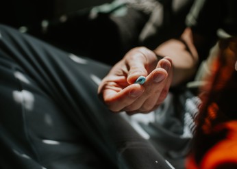 A hand holds a blue PrEP pill