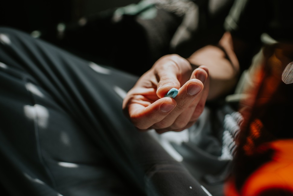 A hand holds a blue PrEP pill