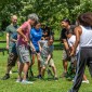 Adults and children play lacrosse outside