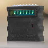A small black device contains test tubes that glow green