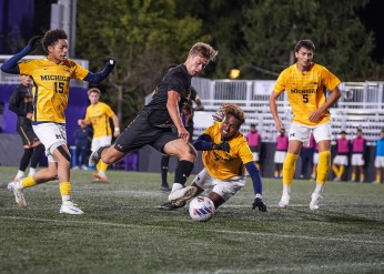 A Northwestern men's soccer player takes on Michigan players