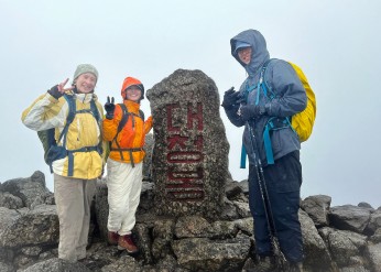 Three hikers pose on the summit of a mountain